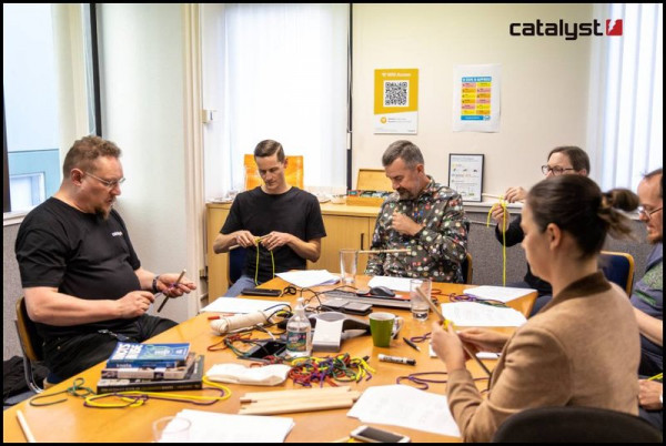 A group of people sitting around a table practicing tying knots.