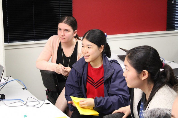 Three students are looking off camera towards a computer screen or instructor