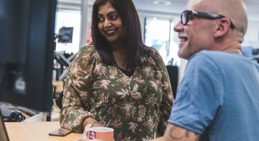 A female and male Catalyst employees huddle around a computer and smile at the screen