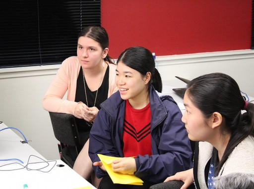Three students are looking off camera towards a computer screen or instructor